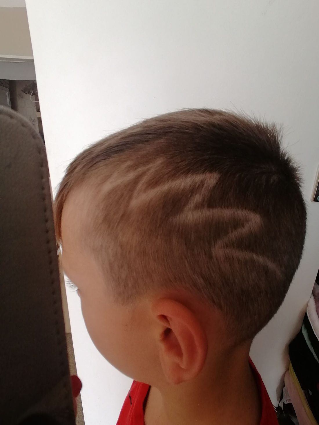 Zygzak wycięty we włosach na boku głowy chłopca, widok z boku
