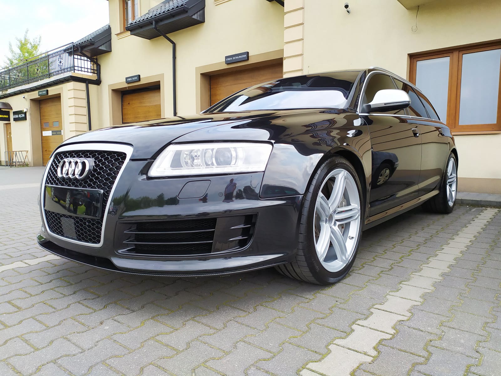 Czarne Audi RS6 Avant przed studiem z szyldami