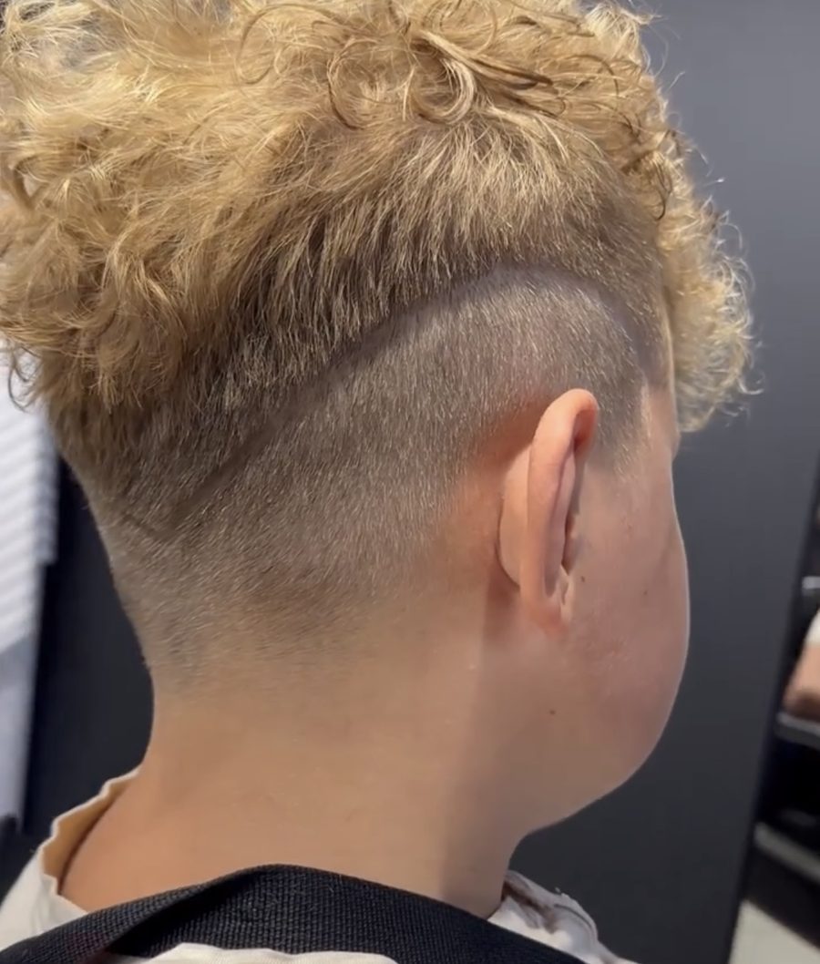 Kręcone blond włosy na górze i bardzo krótkie boki